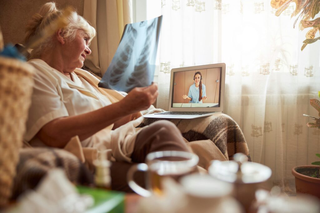 An elderly lady talking to a nurse via her laptop