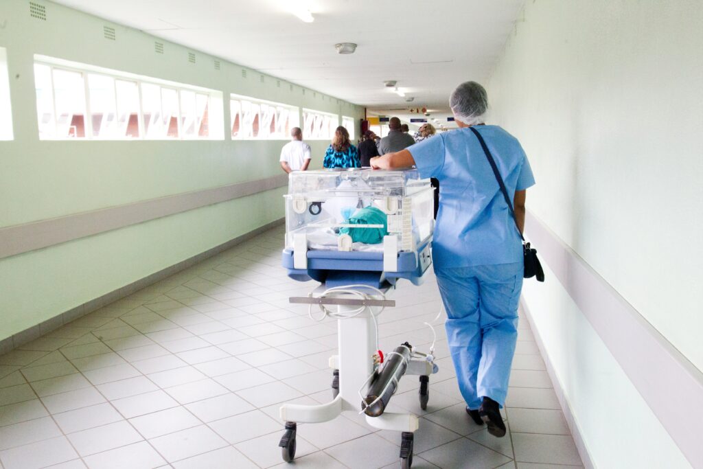 Nurse pushing a baby in a crib down a hospital corridor